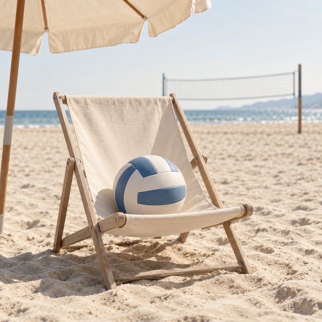 A beach volleyball relaxes in a deckchair beside an empty court.